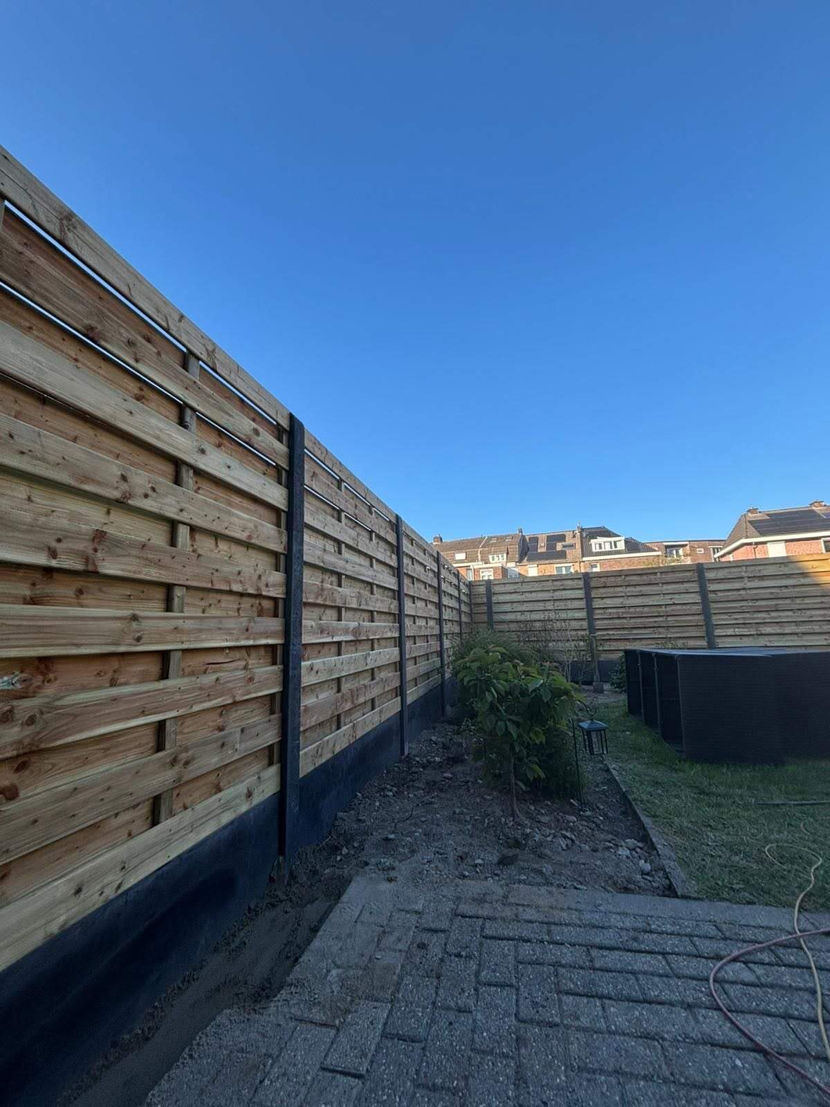 Houten schutsel op een antracietkleurige betonnen onderplaat in een tuin in Heers