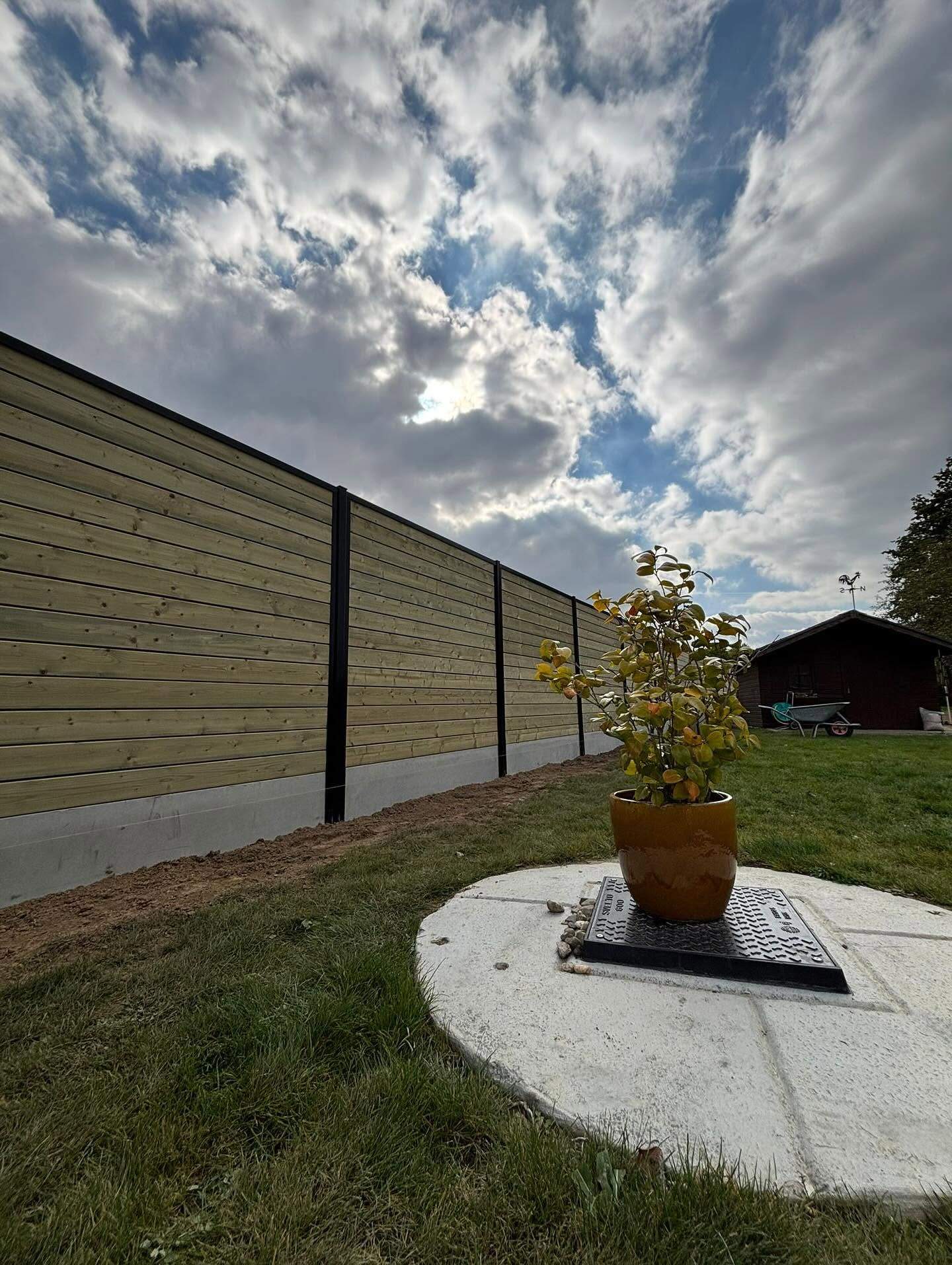 Houten schutsels op betonplaat langs het gazon.