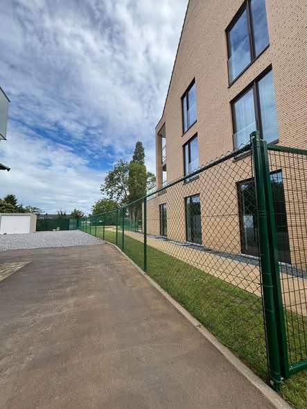 Draadhekwerk met poort bij een appartementsgebouw in Zolder.