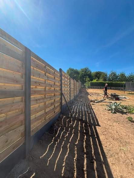Houten schutsels op zwarte betonpalen.
