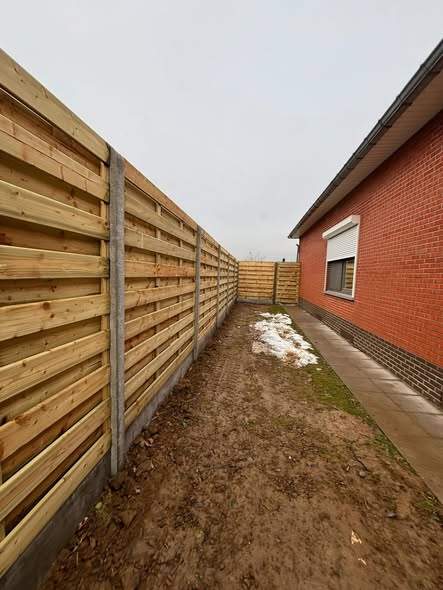 Houten schutsels op betonpalen, geplaatst in de sneeuw.