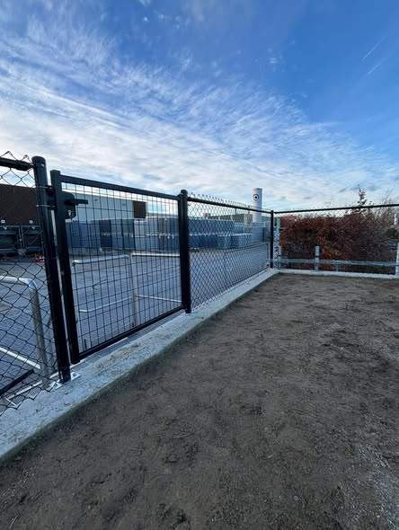 Draad op betonplaat met poort, rond een bedrijfsterrein.